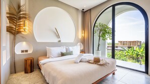 A modern bedroom with a large bed, a round wall-mounted light, and a view of greenery outside. - Unu Villa by Betterplace (Canggu)