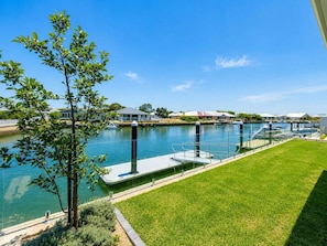 A marina with a dock, a grassy area, and houses in the background.