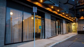A modern building with large windows, a loading zone sign, and a well-lit entrance. - Central Lofts Unit 3 (Queenstown)