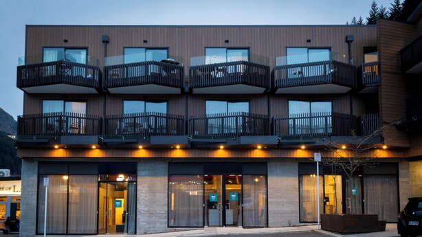 A modern building with multiple balconies, large glass doors, and a parking area. - Central Lofts Unit 3 (Queenstown)