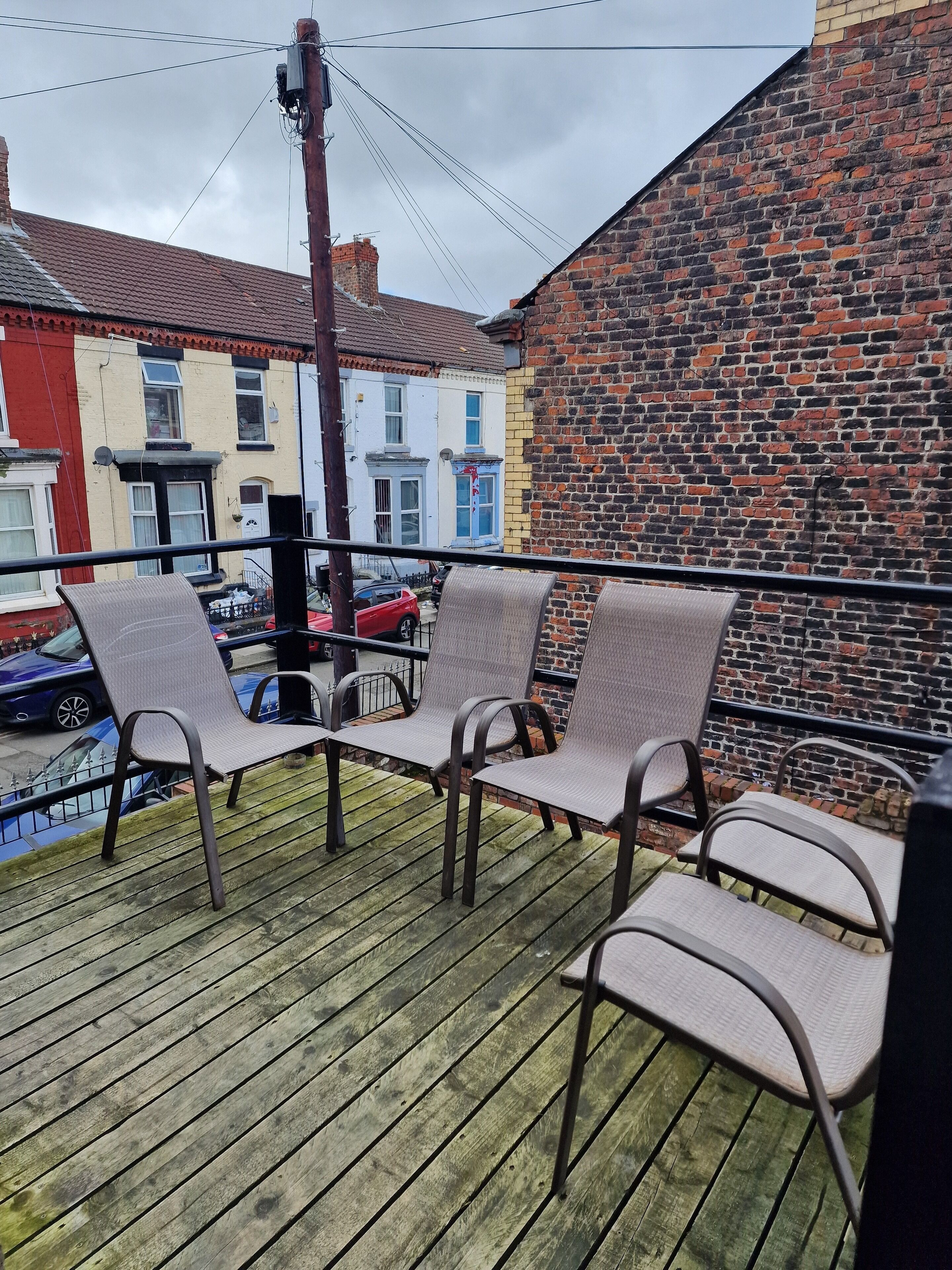 A balcony with metal chairs and a wooden deck.