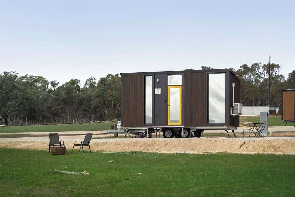 Een kleine, moderne mobiele woning met een schuifdeur, geplaatst op een aanhanger.