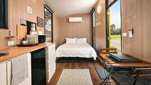 Une pièce compacte comprenant un lit, une kitchenette et donnant sur une vue agréable grâce à une grande fenêtre.