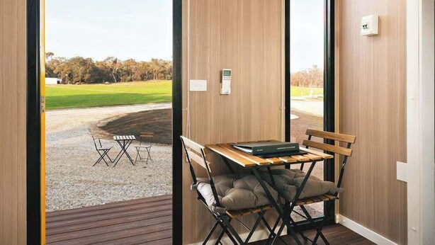 Une pièce moderne avec un plancher en bois, une table sur laquelle se trouve un livre et une chaise.
