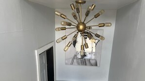 A modern staircase with a unique chandelier and a framed picture above it. - Welcome To The Great Place Of Life (Saskatoon)