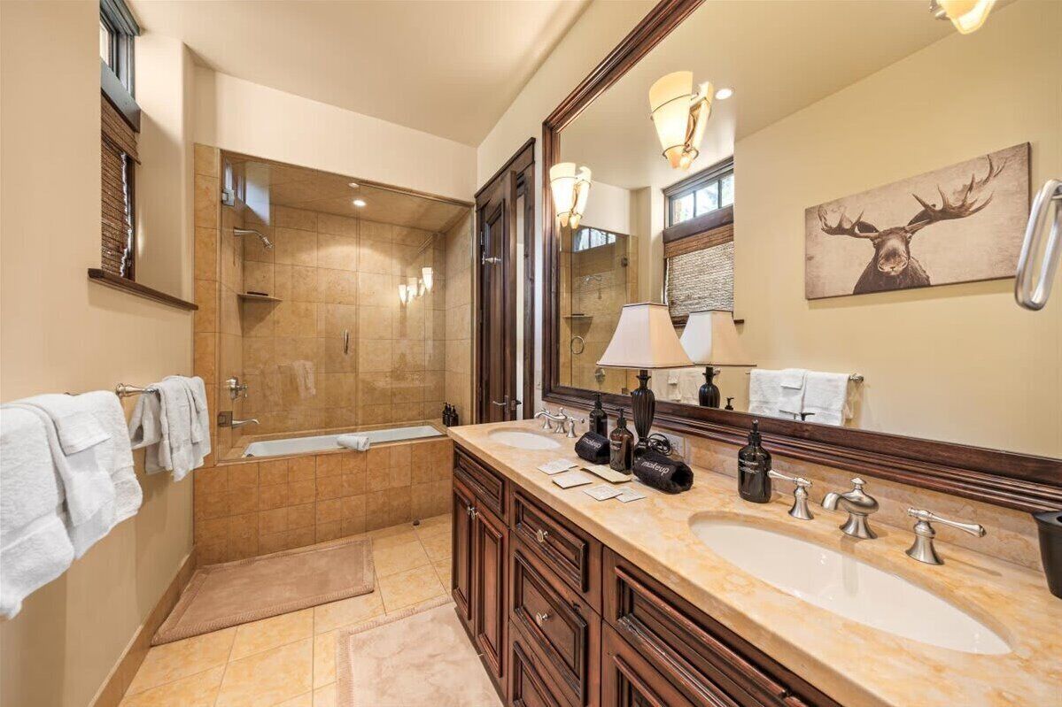 Une salle de bain moderne avec un grand miroir, deux lavabos, une baignoire et une douche.
