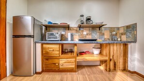 Een kleine keuken met een koelkast, magnetron en houten kastjes.