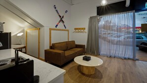 Et moderne hotelværelse med en brun sofa, et rundt sofabord og en skiløber-relateret dekoration på væggen.