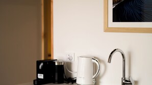 Et moderne køkken med en indbygget opvaskemaskine, kaffemaskine og en hvid kop på bordet.