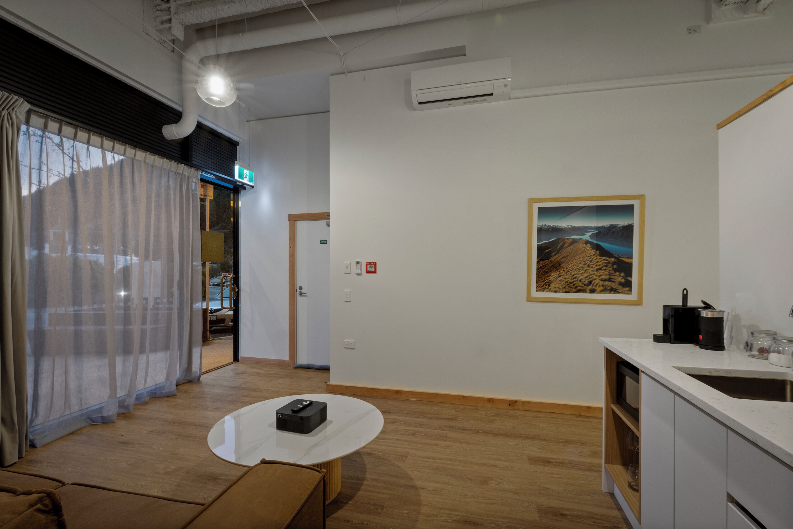 A modern interior with a kitchen area, a dining table, and a sofa.