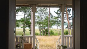 A wooden porch with a view of a grassy field and trees. - Stay North - Honkala (Turku)