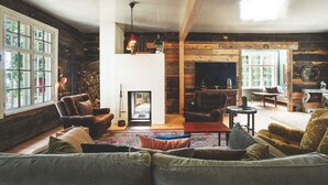A cozy living room with a fireplace, wooden walls, and large windows. - Stay North - Honkala (Turku)
