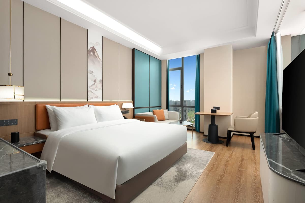 Una habitación de hotel moderna con una cama grande, un escritorio, una silla y un televisor.