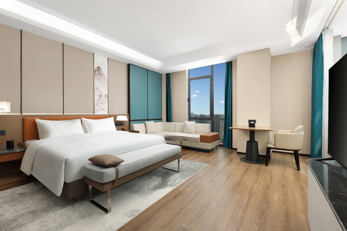 Una habitación de hotel moderna con una cama grande, un sofá, un escritorio y un televisor.
