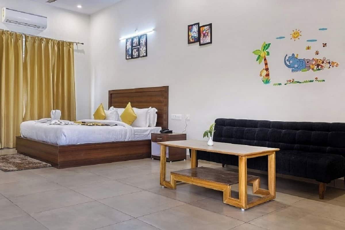 A hotel room with a bed, a wooden nightstand, a black sofa, and a small table.