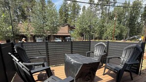 Une terrasse dotée de mobilier d’extérieur, comprenant des chaises et une table, entourée d’une terrasse en bois et d’une clôture en métal.