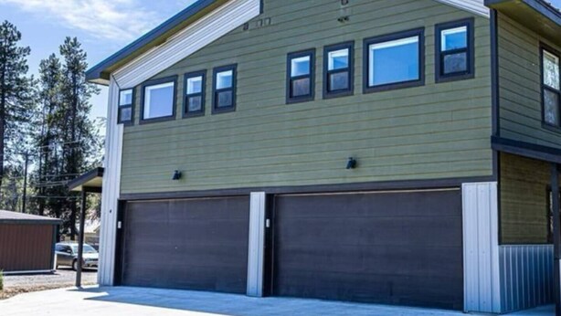 Un bâtiment à deux étages doté d’un garage et d’une allée couverte.