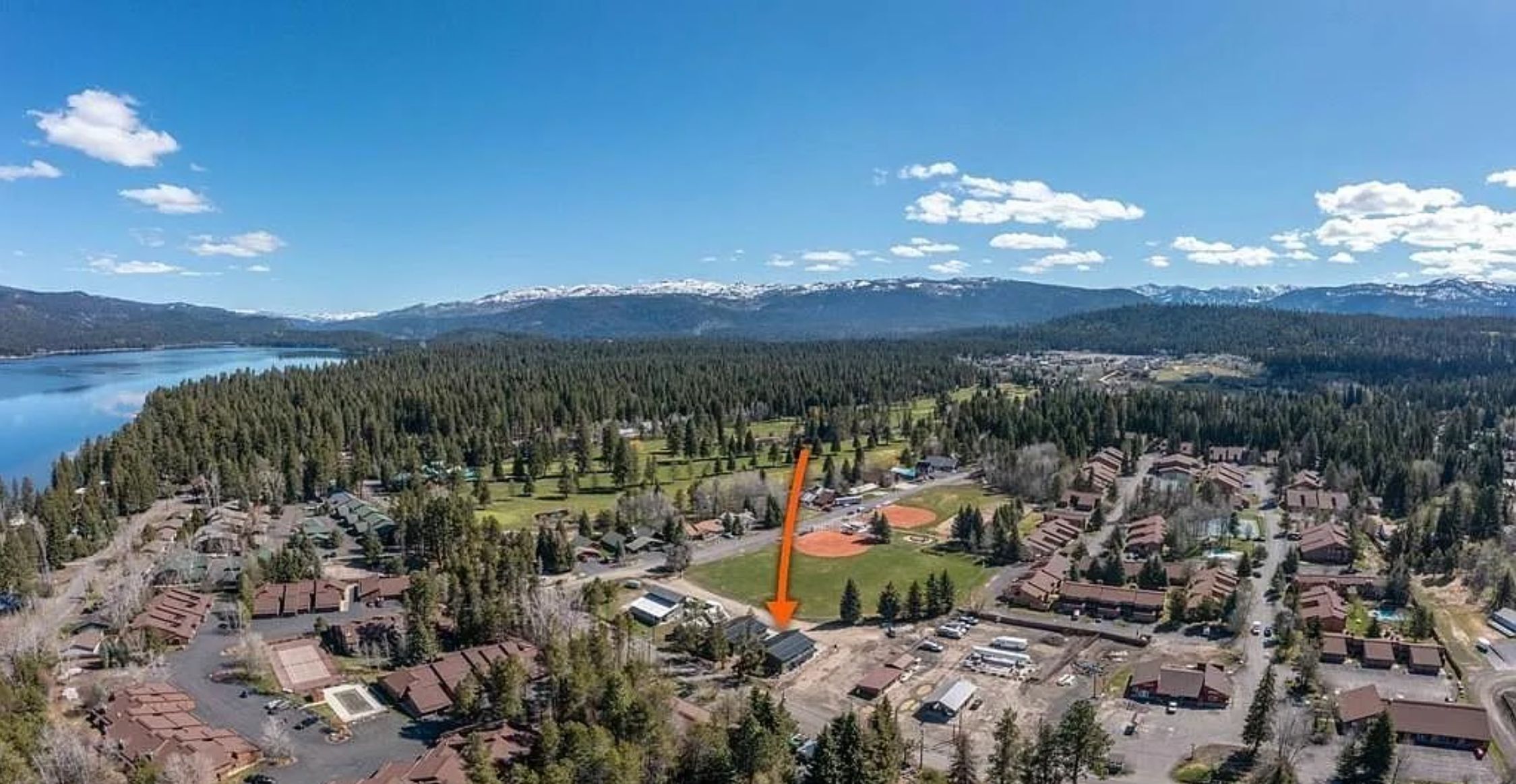 Vista aérea de una zona residencial con casas, un campo deportivo y un lago.