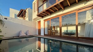 Una casa moderna con un porche acristalado y una piscina.