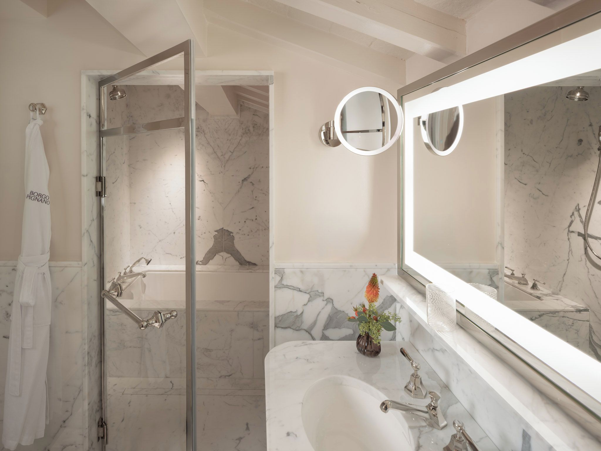 A bathroom with a glass shower enclosure, a marble sink, and a large mirror.