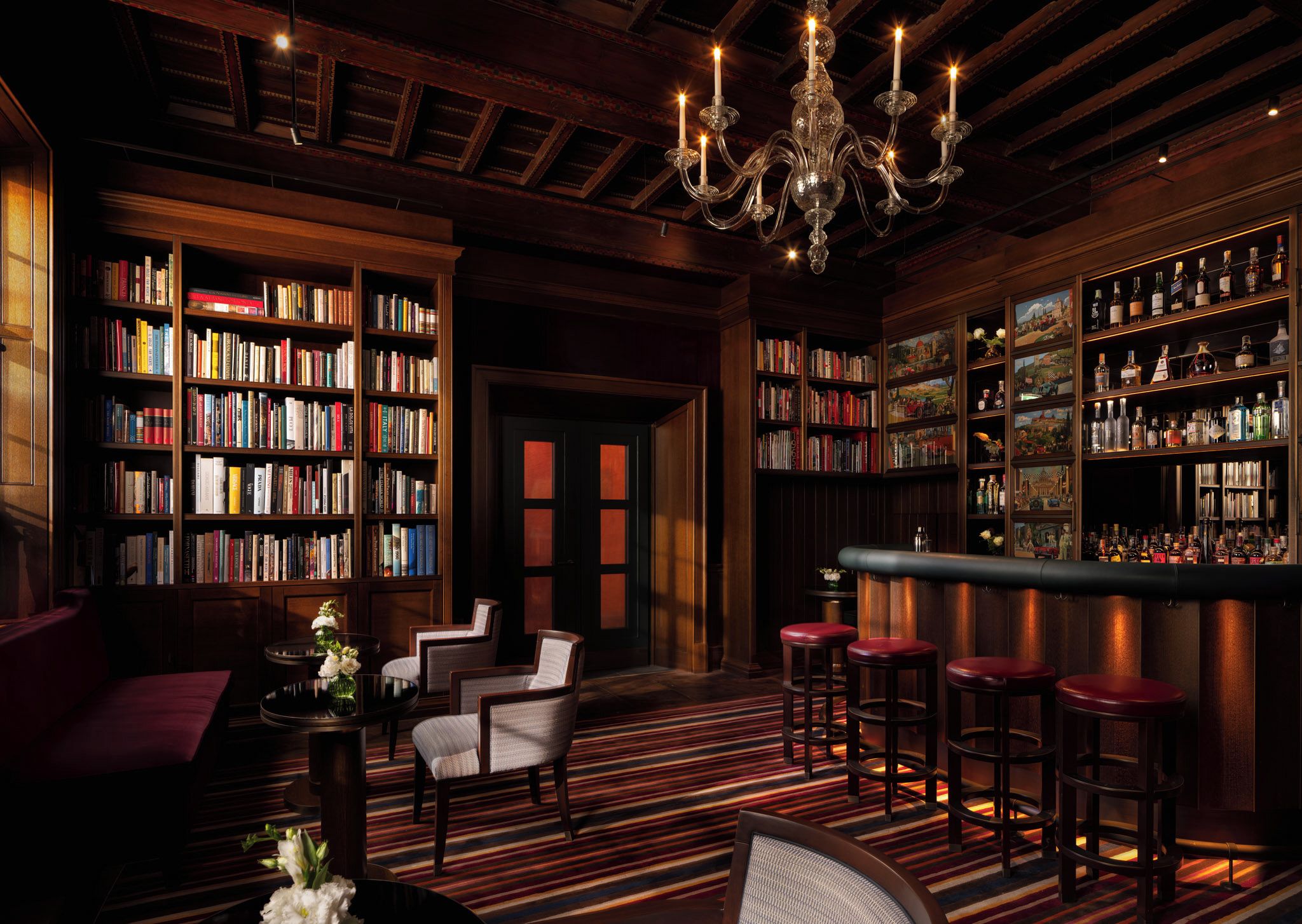 A library with bookshelves, a bar area, and seating.