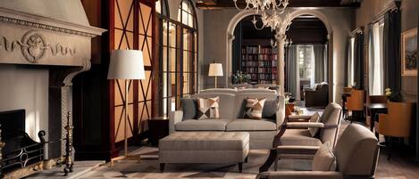 A spacious living room with a fireplace, bookshelves, and a chandelier.