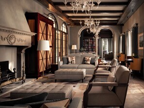 A spacious living room with a fireplace, bookshelves, and a chandelier. - Borgo Pignano Florence (Florence)