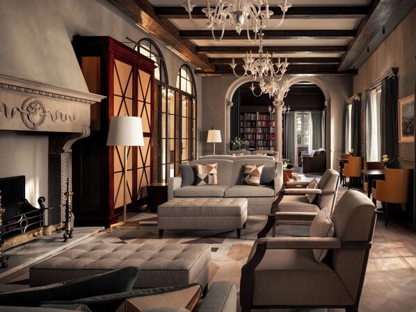 A spacious living room with a fireplace, bookshelves, and a chandelier.