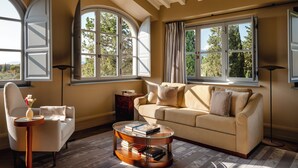 A room with a sofa, a glass coffee table, a chair, and large windows with curtains. - Borgo Pignano Florence (Florence)