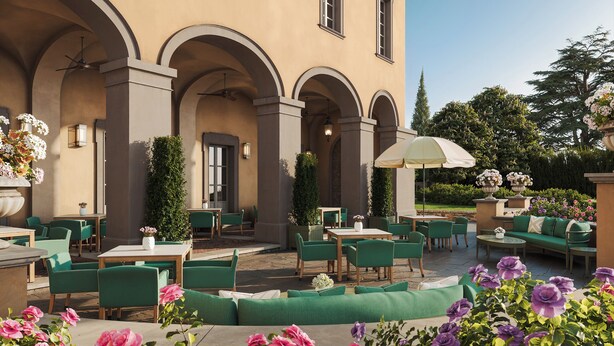 An outdoor patio with green seating, tables, and a large umbrella. - Borgo Pignano Florence (Florence)