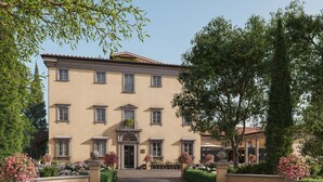 A large, multi-story building with a symmetrical facade, a central entrance, and a well-maintained garden with various plants and flowers. - Borgo Pignano Florence (Florence)
