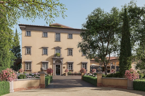 A multi-story building with a symmetrical facade, a central entrance, and a well-maintained garden with various plants and flowers.
