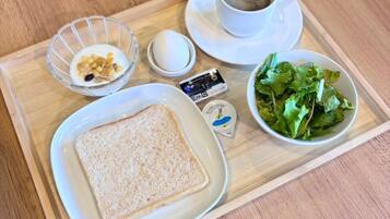 A tray with a slice of white bread, a small bowl of salad, a cup of coffee, and a container of margarine.