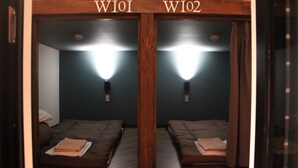 Una habitación con espejos y dos camas, identificadas como W101 y W102, cada una con una lámpara de noche y una toalla doblada sobre la cama.