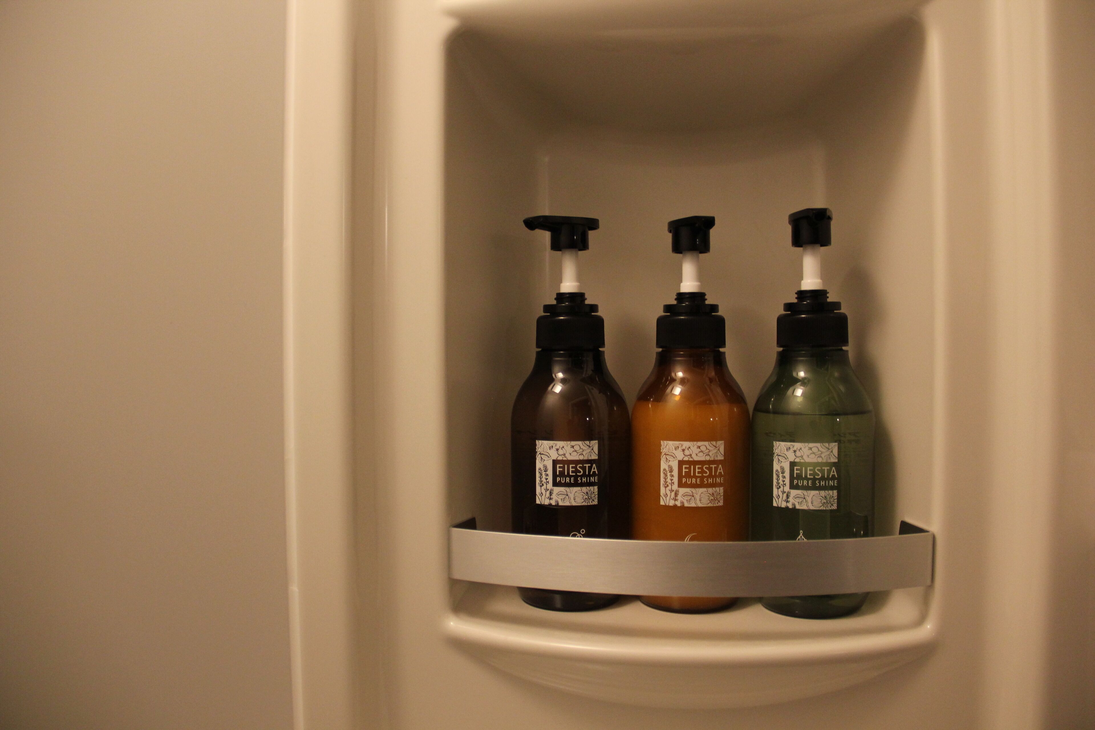 Un estante de baño con tres botellas de jabón de manos 'Fiesta Pure Shine'.