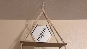 A macrame wall hanging with the word "inspire" on a hexagonal frame, suspended from a wooden structure with macrame ropes. - Simplicity Stays NOLA (New Orleans)