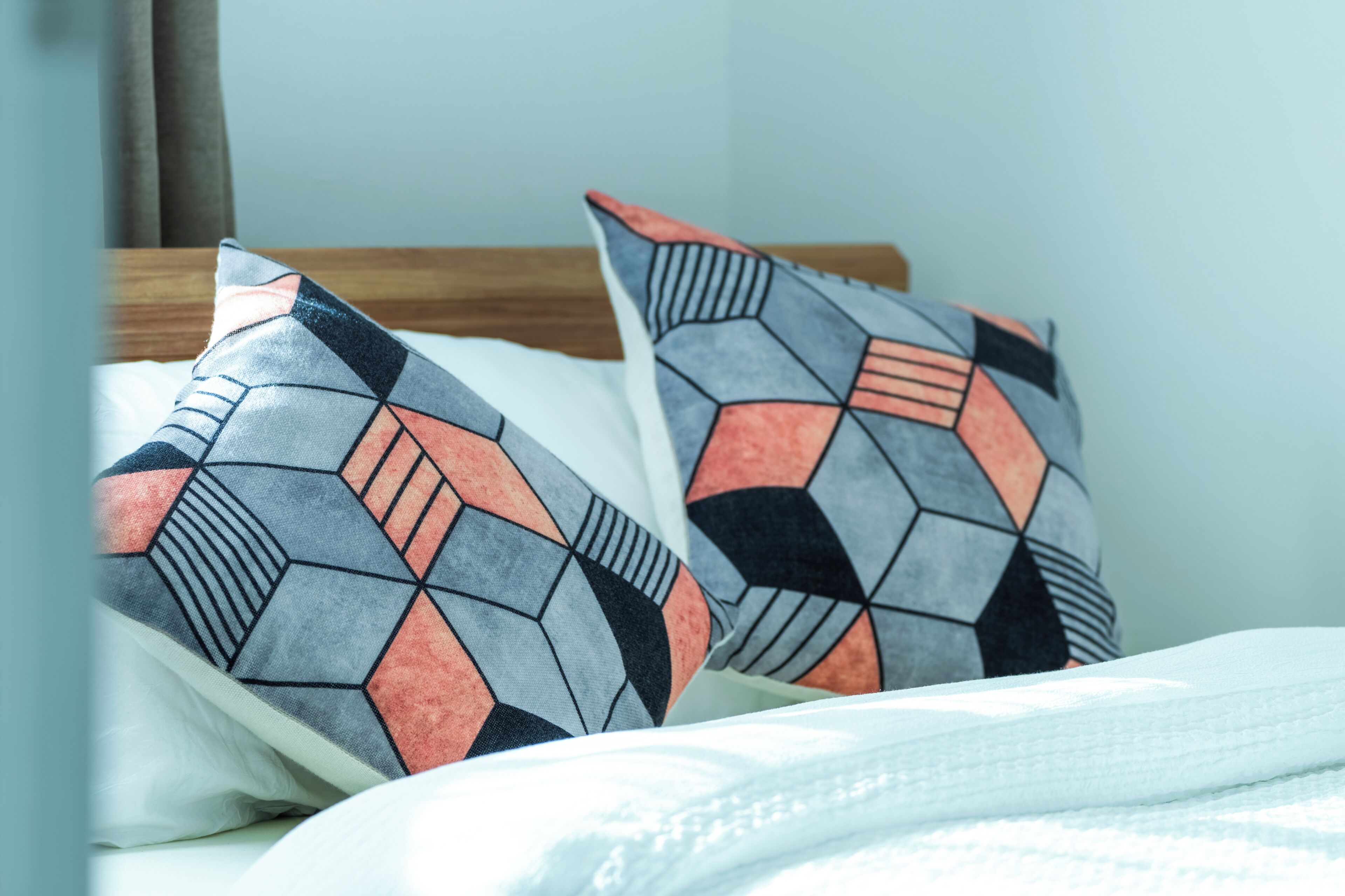 A bed with two pillows featuring a geometric pattern.