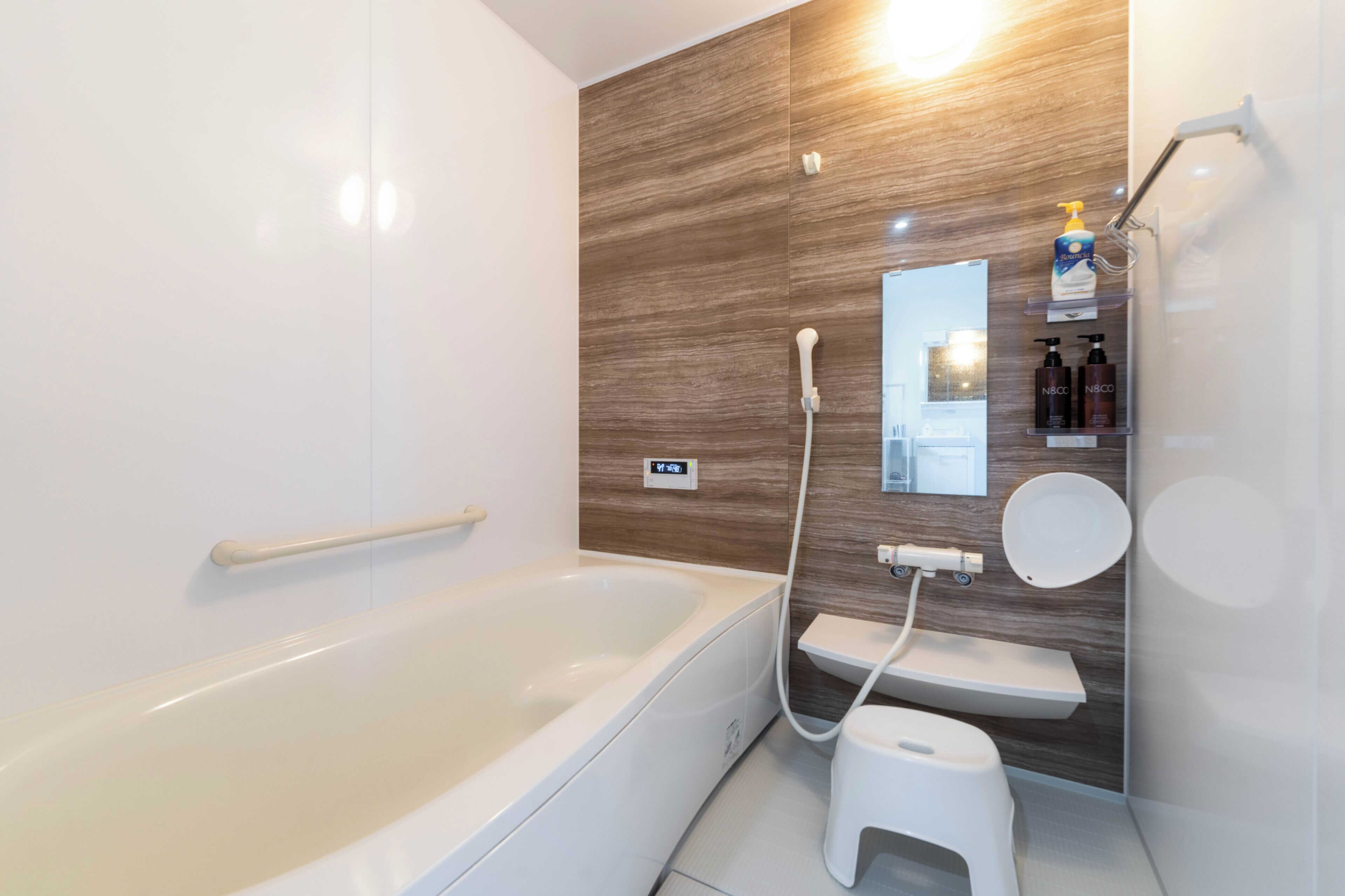 A modern bathroom with a bathtub, a toilet, a shower, and a vanity with toiletries.