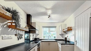 Een moderne keuken met witte kasten, een zwart aanrecht en een raam dat natuurlijk licht binnenlaat.