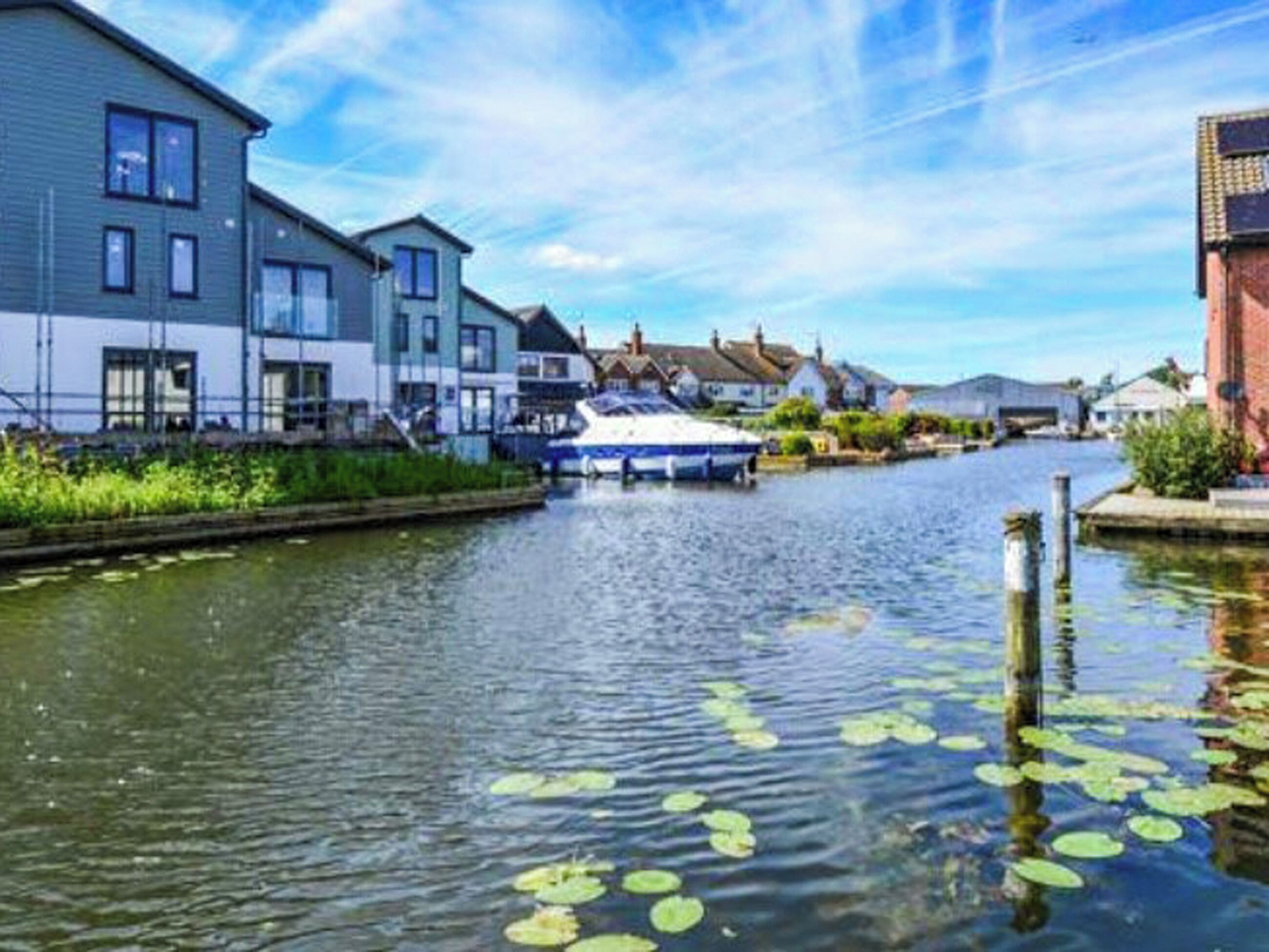 Un canal où est amarré un bateau-maison, entouré d’immeubles d’habitation.