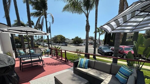A covered outdoor seating area with a red deck, a sofa, and a table. - Iris Suite I Walk to Shops, Dining + Bay (Coronado)