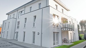 Moderni kaksikerroksinen rakennus, jossa on tasakatto, suuret ikkunat ja parveke.