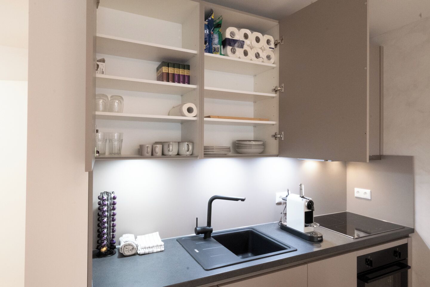 Eine moderne Küche mit integriertem Spülbecken, einer Kaffeemaschine und Regalen voller Küchenausstattung.