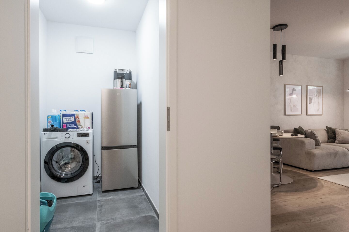 A compact living space with a washing machine, a refrigerator, and a sofa.