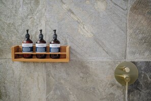Een houten plank met drie flessen Sensatia Botanicals producten tegen een stenen muur.