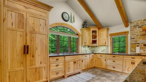 Una cocina amplia con armarios de madera, un muro de acento de piedra y ventanas grandes con vistas al verdor.
