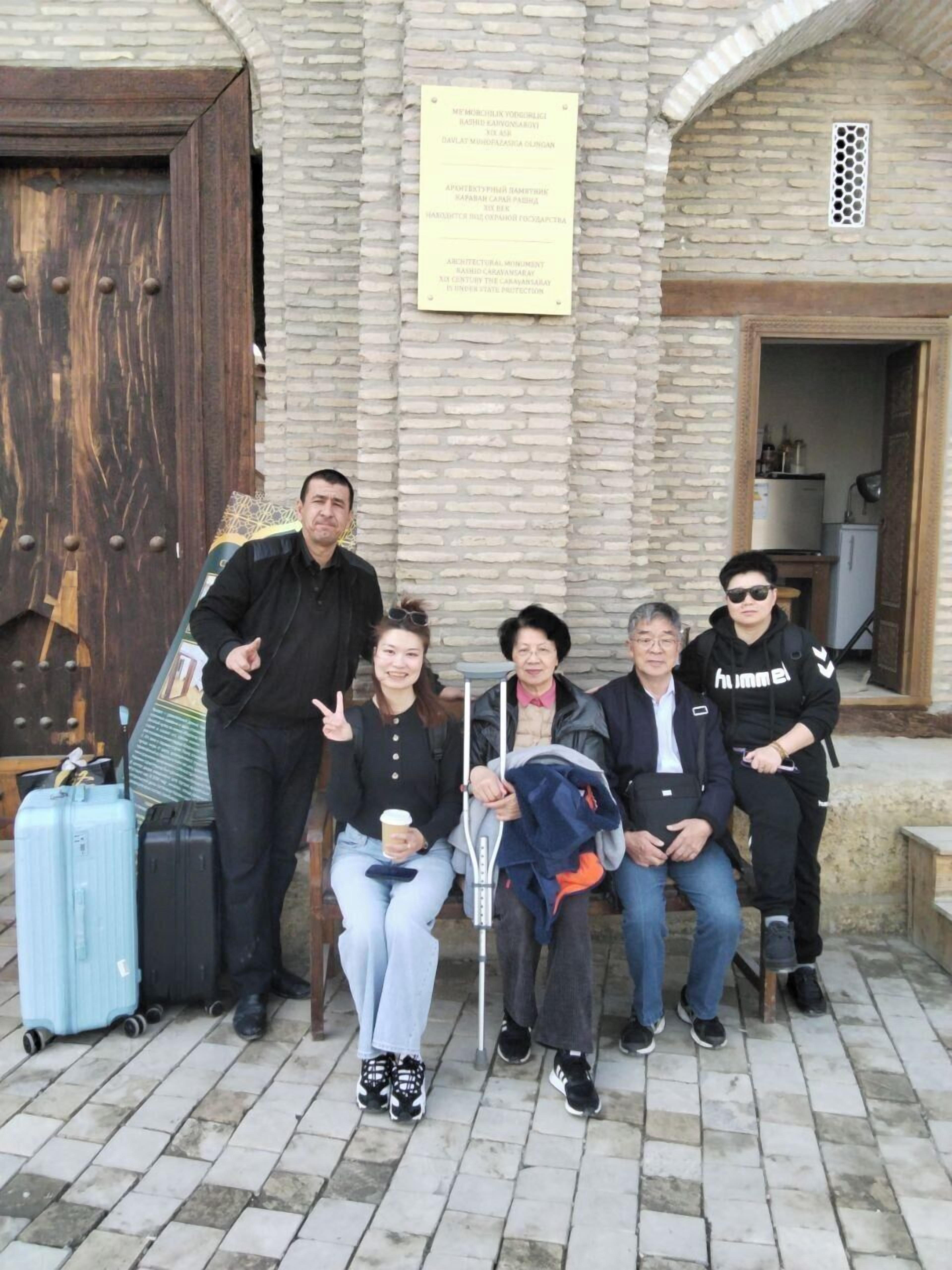 Un grupo de personas frente a un edificio con fachada de piedra y puerta de madera.