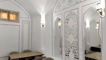 Un espace repas doté d’un plafond haut, de murs à motifs et d’un grand miroir.