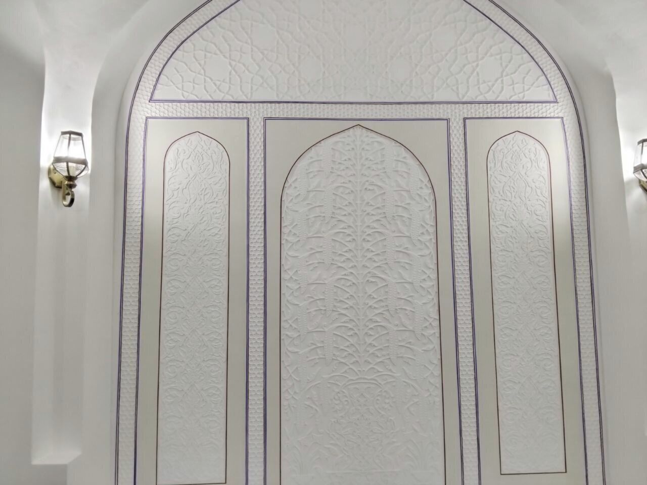 A white door with intricate embossed patterns and a decorative arch above it.