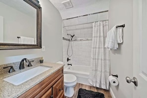 Een badkamer met een wastafel, spiegel, toilet en douche.
